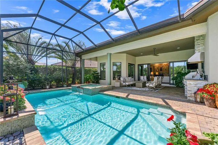Combined pool / hot tub featuring a lanai, an outdoor kitchen with living area, a patio, and a sunroom
