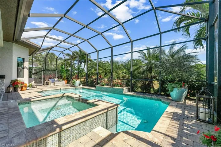 Relaxing pool / spa with a sunroom, a patio area, and a lanai
