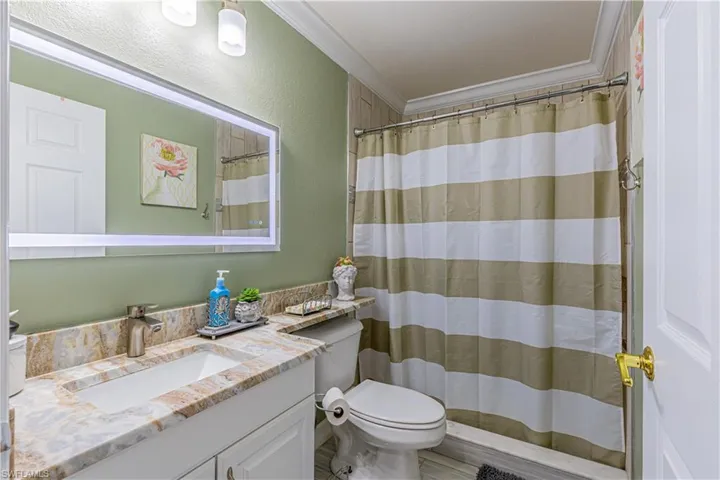 Bathroom with crown molding, toilet, and vanity with extensive cabinet space