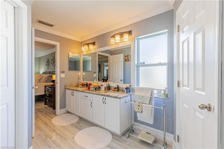 Bathroom featuring crown molding, dual sinks, oversized vanity, and hardwood / wood-style floors