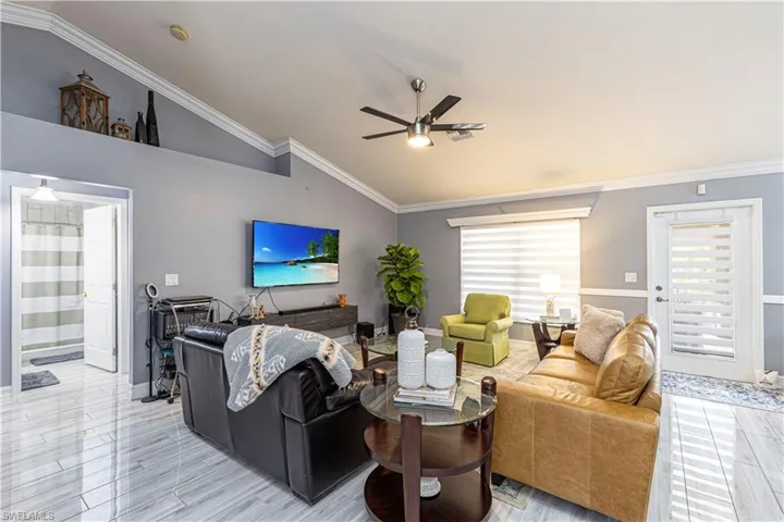 Living room with vaulted ceiling, ceiling fan, and crown molding
