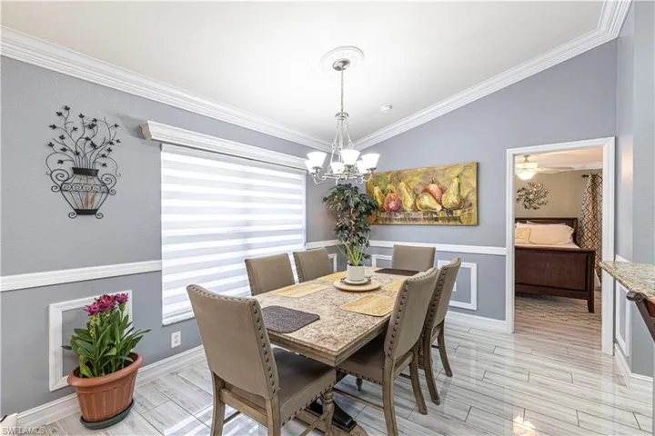 Dining area with ornamental molding, lofted ceiling, and ceiling fan with notable chandelier