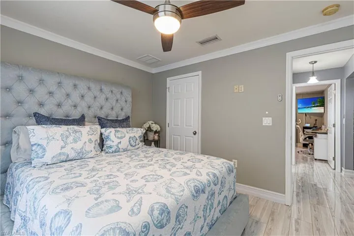 Bedroom with ceiling fan, light hardwood / wood-style flooring, and ornamental molding