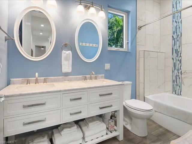 Bathroom with double vanity, bathtub / shower combination, and wood tiled floors