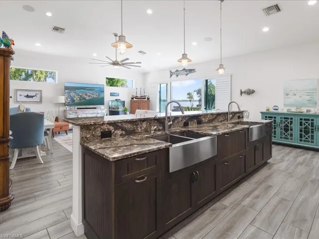 Kitchen with dark wood finish cabinets, pendant lighting, dark stone countertops, and healthy amount of natural light