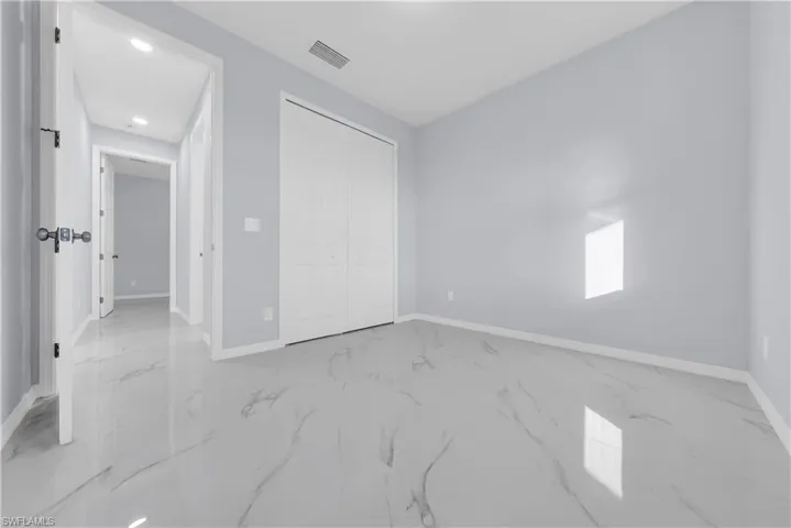 Unfurnished bedroom with marble tiled flooring, a closet, and recessed lighting