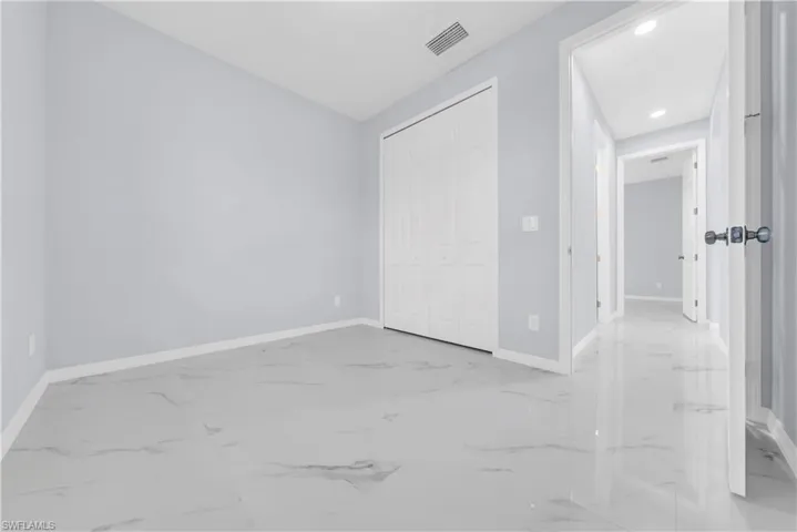 Unfurnished bedroom featuring light marble finish floors, a closet, and recessed lighting