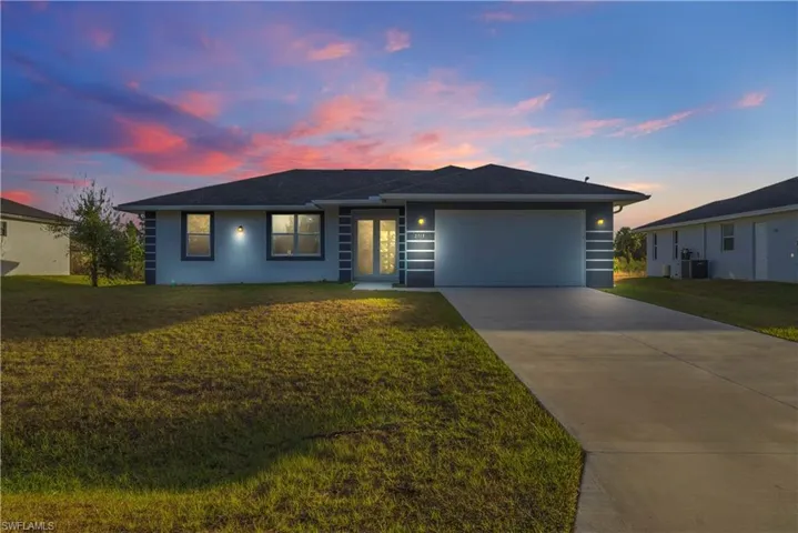 View of front facade with driveway, a garage, a front lawn, and stucco siding