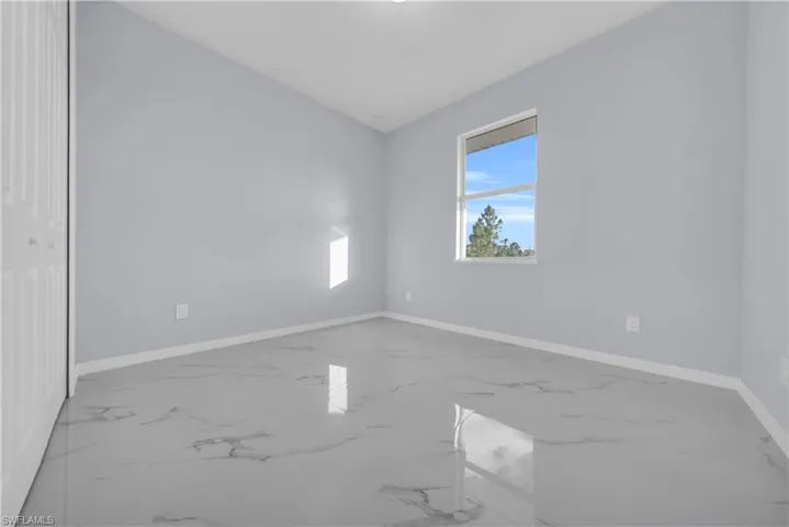 Unfurnished bedroom featuring baseboards and marble tiled floors