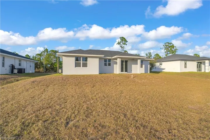 Back of property with a yard and stucco siding