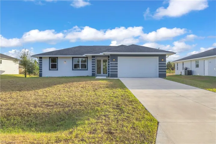 View of front of property featuring a front lawn, driveway, a garage, and stucco siding
