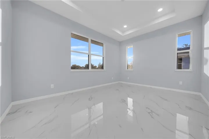 Unfurnished room featuring recessed lighting, marble tiled flooring, and a raised ceiling