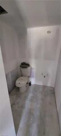 Bathroom with concrete floors, toilet, and lofted ceiling
