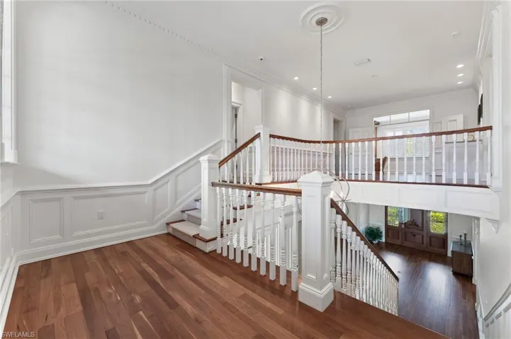 Stairs featuring a healthy amount of sunlight, wood finished floors, and a decorative wall