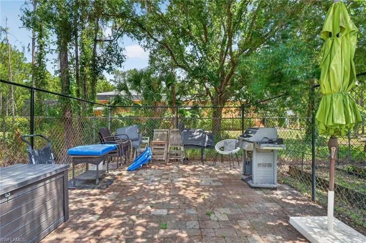 Paved patio area featuring brick-patterned pavers and a chain-link fence