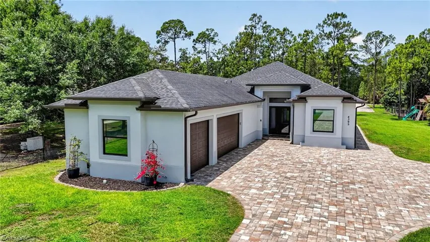 Contemporary single-story residence featuring a gray shingle roof and a paver driveway