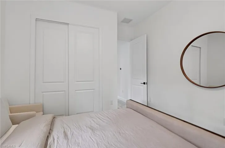 White interior room featuring a two-panel sliding closet door, white trim, and a contemporary round wall mirror