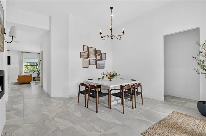 Spacious dining area featuring a modern chandelier, light-toned flooring, and crisp white walls