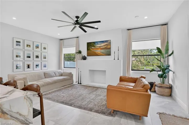 Spacious living area featuring large format tile flooring, a modern ceiling fan, and a built-in fireplace structure