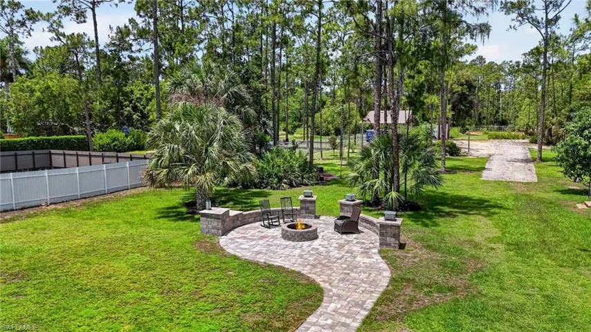 Expansive outdoor living area featuring a paver patio with a built-in fire pit, stone accent walls, and a stone-clad fire feature