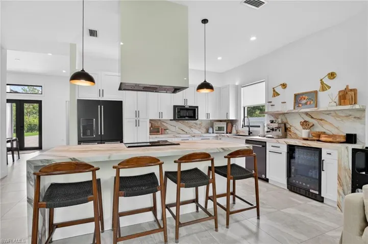 Gourmet kitchen with waterfall island, custom cabinetry, integrated range hood, and premium appliances