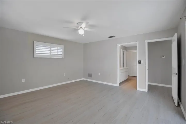 Owners Primary Bedroom leading to Bath & Dressing Areas. bedroom with light wood-type flooring, ceiling fan, and connected bathroom