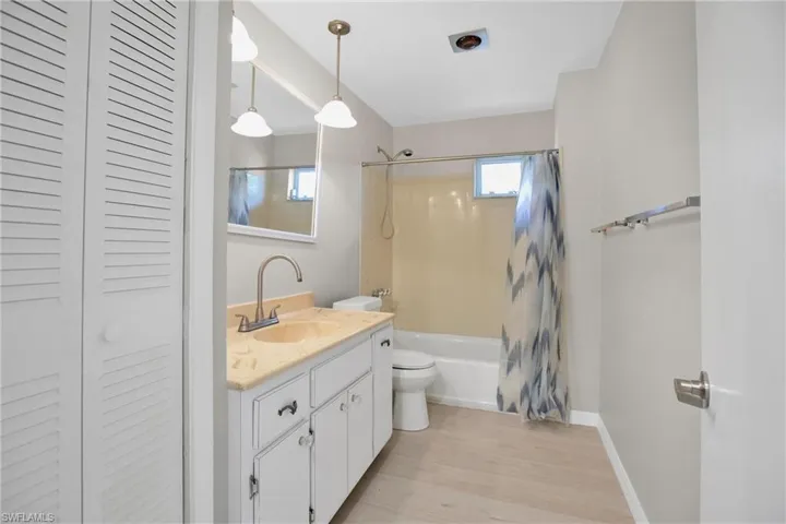 2nd Full bathroom set between 2nd and 3rd bedrooms. Featuring vanity, toilet, hardwood / wood-style flooring, and shower / bath combination with curtain