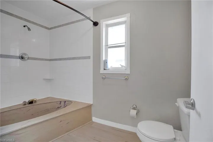 Owners Bathroom featuring wood-type flooring, Owersized tub, heat/drying lamp and toilet