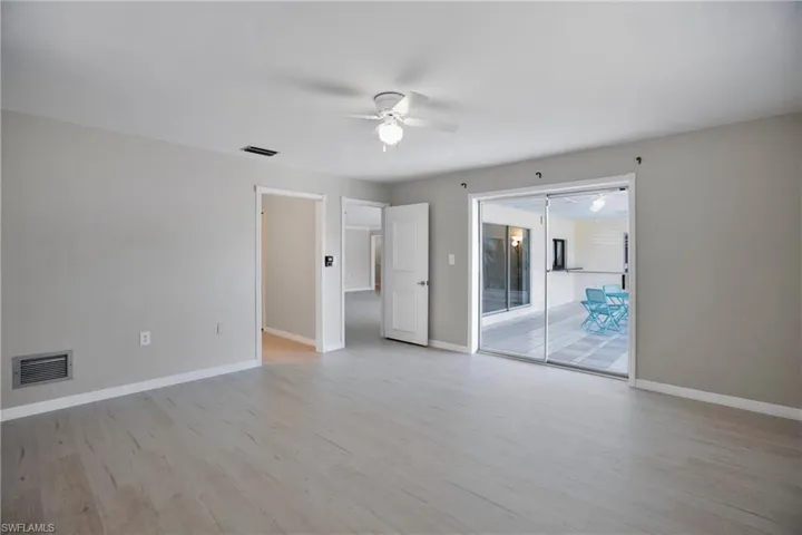 Owners Primary Bedroom with door to Lanai, featuring light wood-type flooring and ceiling fan