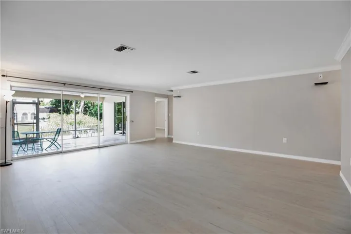 Living Room. Surround Sound wired. Showing entry to Lanai and Owners Suite. Featuring hardwood / wood-style floors and crown molding