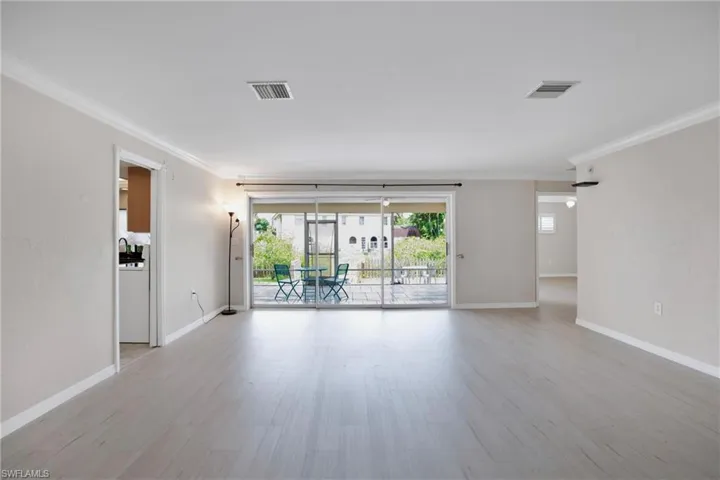 Living Rm looking towards Lanai, with light hardwood / wood-style flooring and crown molding