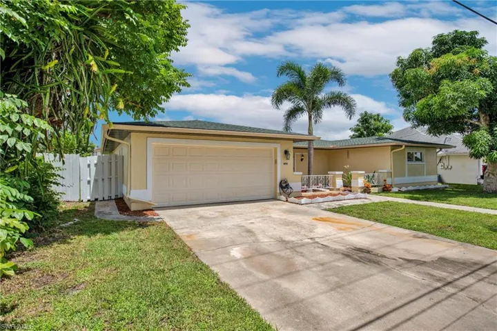 Ranch-style home featuring a garage and a front yard Dragon Fruit And Mango Trees