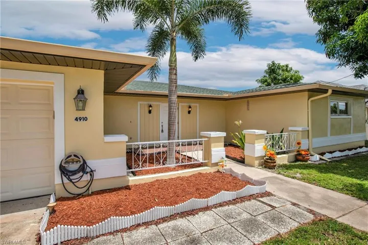 View of front of property with Garage, Courtyard, Palm and Fruit Trees