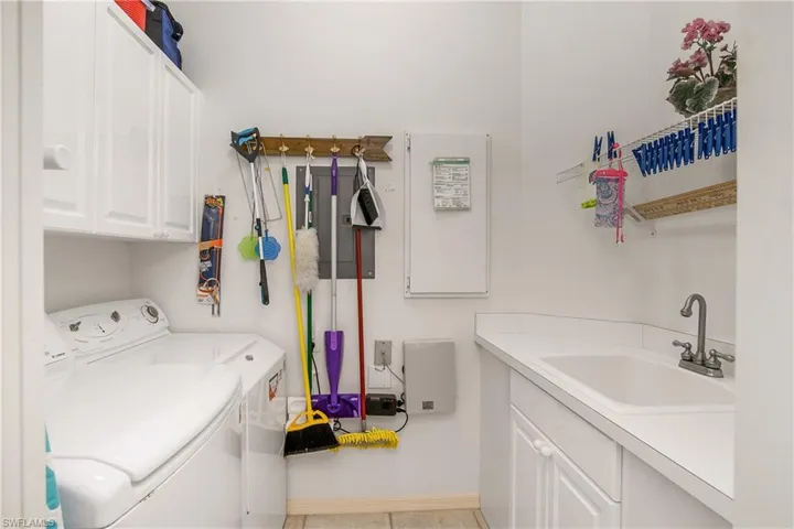 Laundry room with washer and dryer, sink, light tile patterned floors, and cabinets