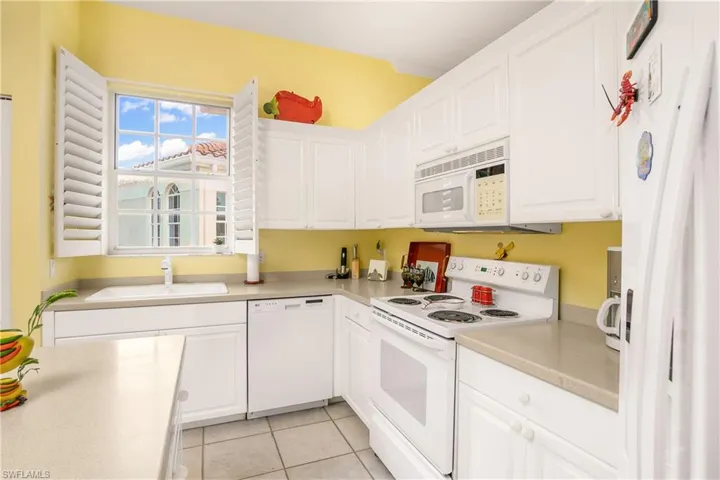 Kitchen with light tile patterned floors, white appliances, white cabinetry, and sink
