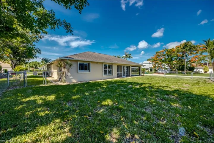 Back of house with a gate, stucco siding, a fenced backyard, and a sunroom