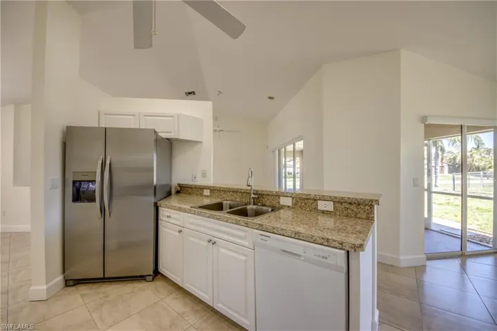 Kitchen featuring stainless steel fridge with ice dispenser, dishwasher, ceiling fan, lofted ceiling, and a peninsula