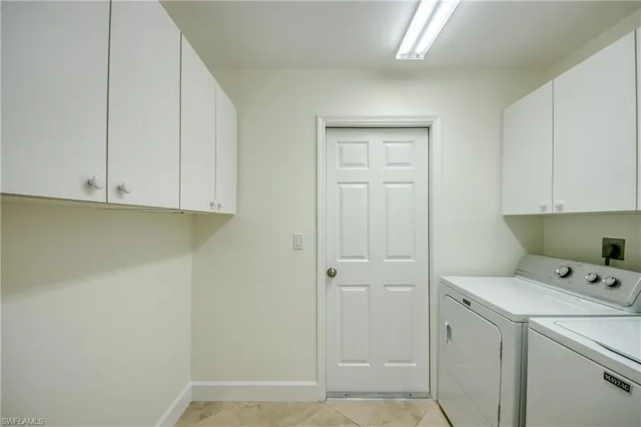 Washroom with cabinet space, washing machine and clothes dryer, and light tile patterned floors