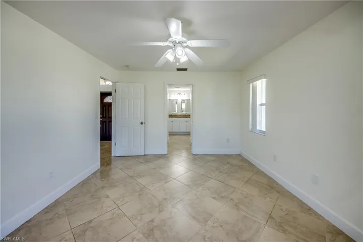 Unfurnished bedroom with ceiling fan and connected bathroom