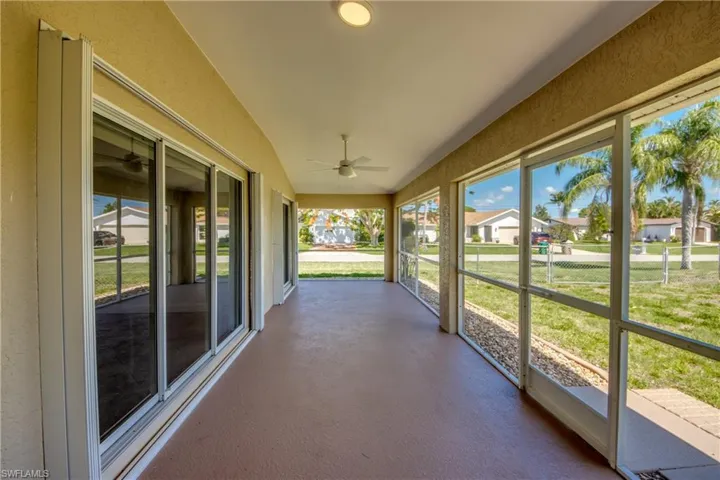 Unfurnished sunroom featuring ceiling fan, lofted ceiling, and a residential view