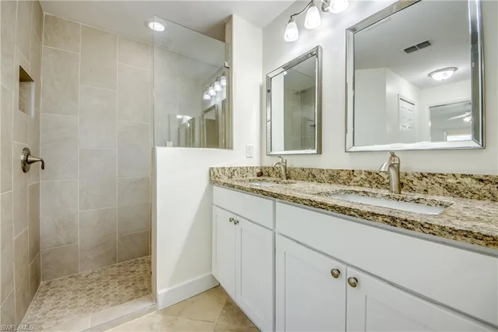 Bathroom featuring double vanity, walk in shower, and tile patterned flooring