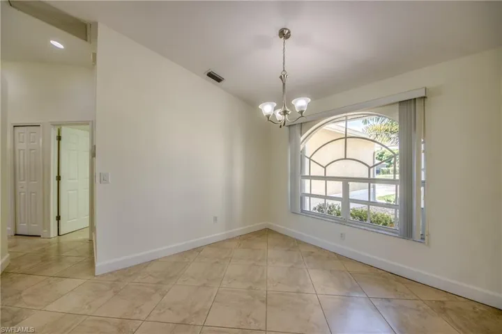Spare room with a chandelier and baseboards