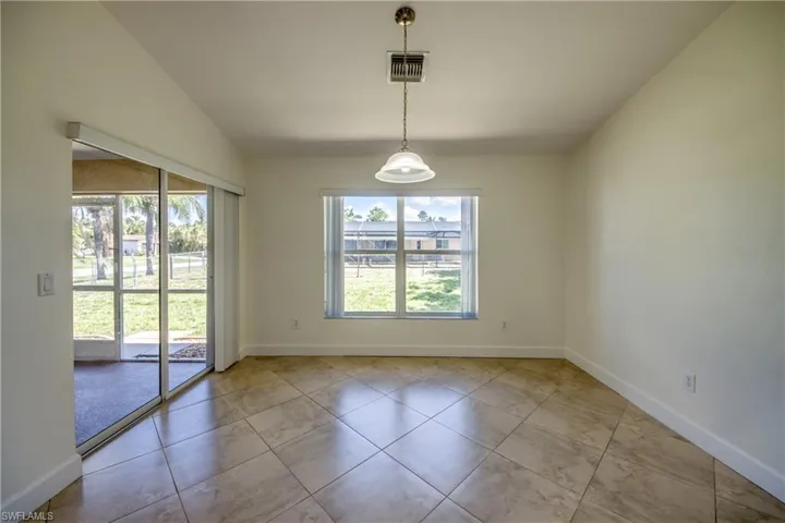 Tiled empty room featuring vaulted ceiling and baseboards
