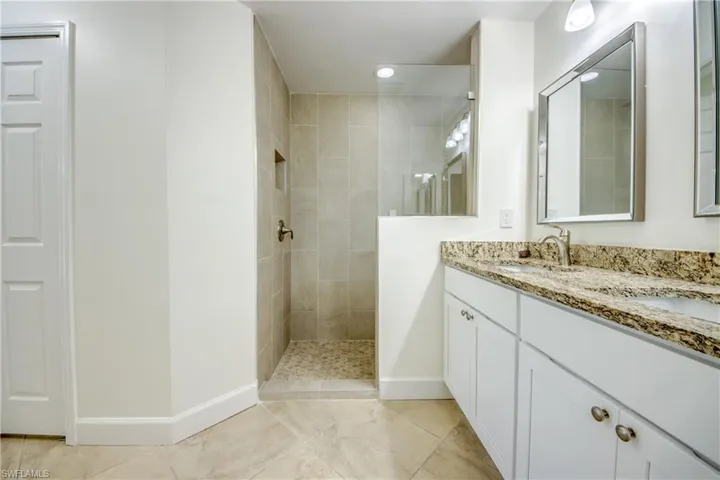 Bathroom with double vanity, walk in shower, and tile patterned floors