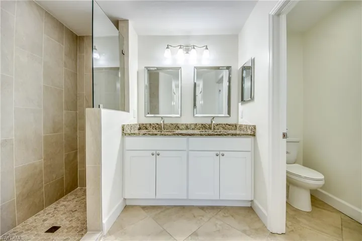 Full bathroom with double vanity, walk in shower, and tile patterned floors