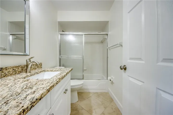 Bathroom with vanity, bath / shower combo with glass door, and tile patterned floors