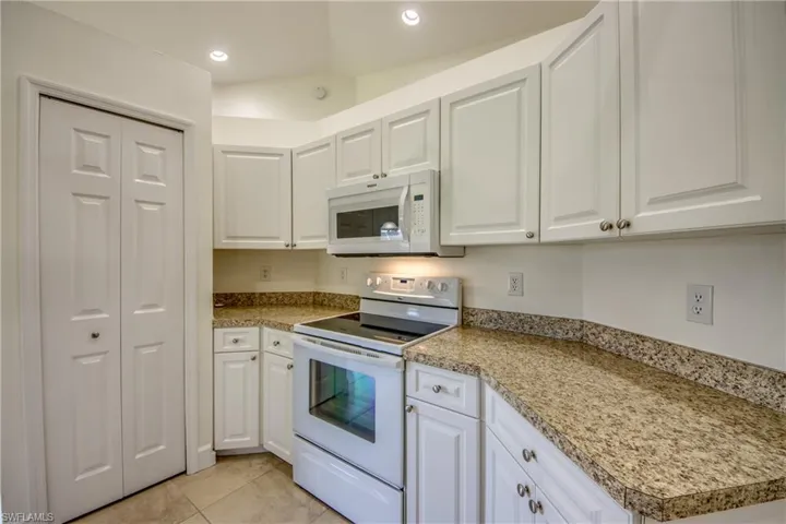 Kitchen featuring white appliances, white cabinets, and recessed lighting