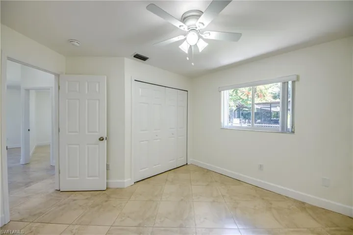 Unfurnished bedroom with a closet, light marble finish floors, and a ceiling fan