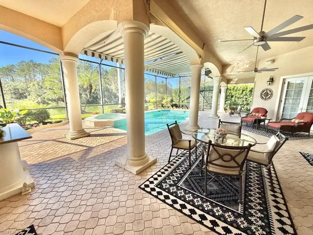 View of patio / terrace with ceiling fan, a swimming pool with hot tub, and glass enclosure