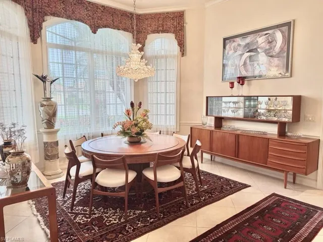 Tiled dining space featuring an inviting chandelier, ornamental molding, and a healthy amount of sunlight